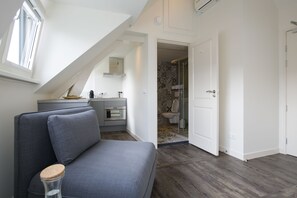 A modern, compact living space with a loft bedroom, kitchenette, and bathroom.