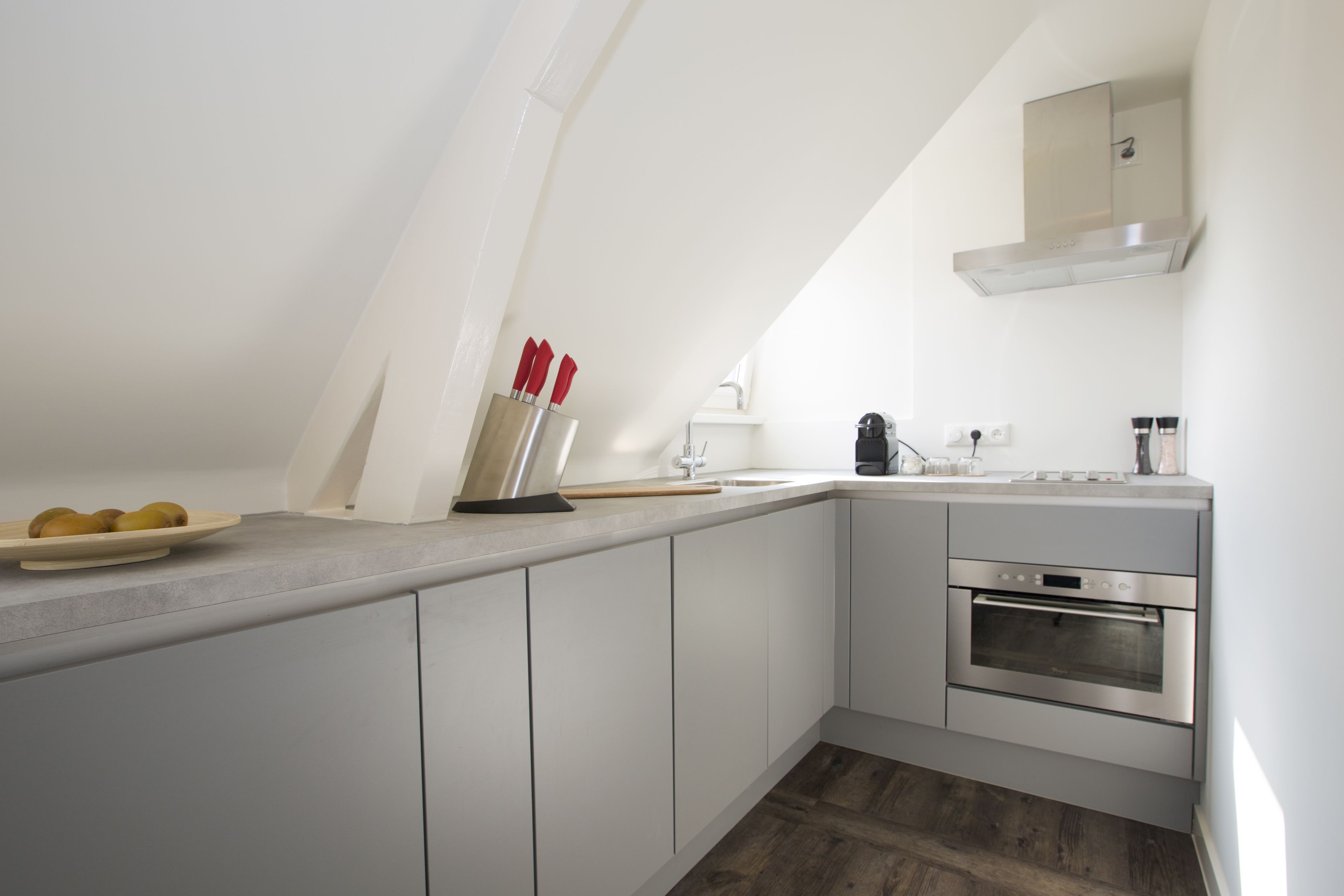 Una cocina moderna con armarios blancos, horno de acero inoxidable y encimera de madera.