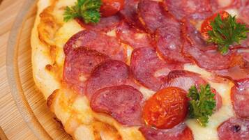 A pizza with pepperoni and parsley on a wooden board.