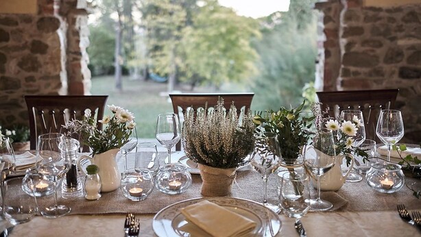 Ett vackert dukat bord för en måltid, med klara glas, ljus och blomsterarrangemang som mittpunkt.