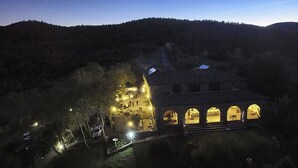 En byggnad med flera valv och en innergård, omgiven av träd och kullar.
