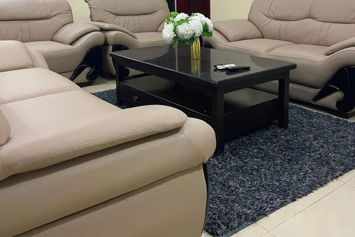 A living room with beige sofas, a black coffee table, and a floral centerpiece.