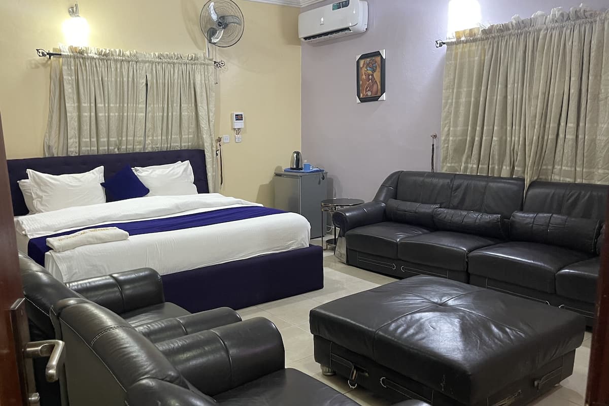 A hotel room with a bed, a sofa, a coffee table, a desk, and a chair.