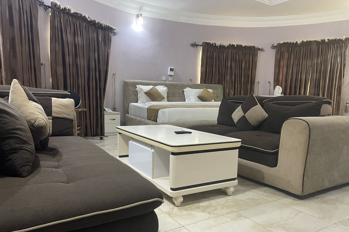 A modern hotel room with a bed, sofa, and a small white table.