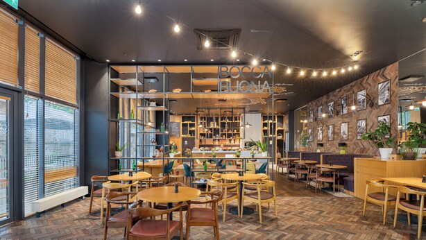 A restaurant interior with wooden herringbone flooring, multiple tables and chairs, and a visible menu board. - Park Inn by Radisson Riga Valdemara (Riga)