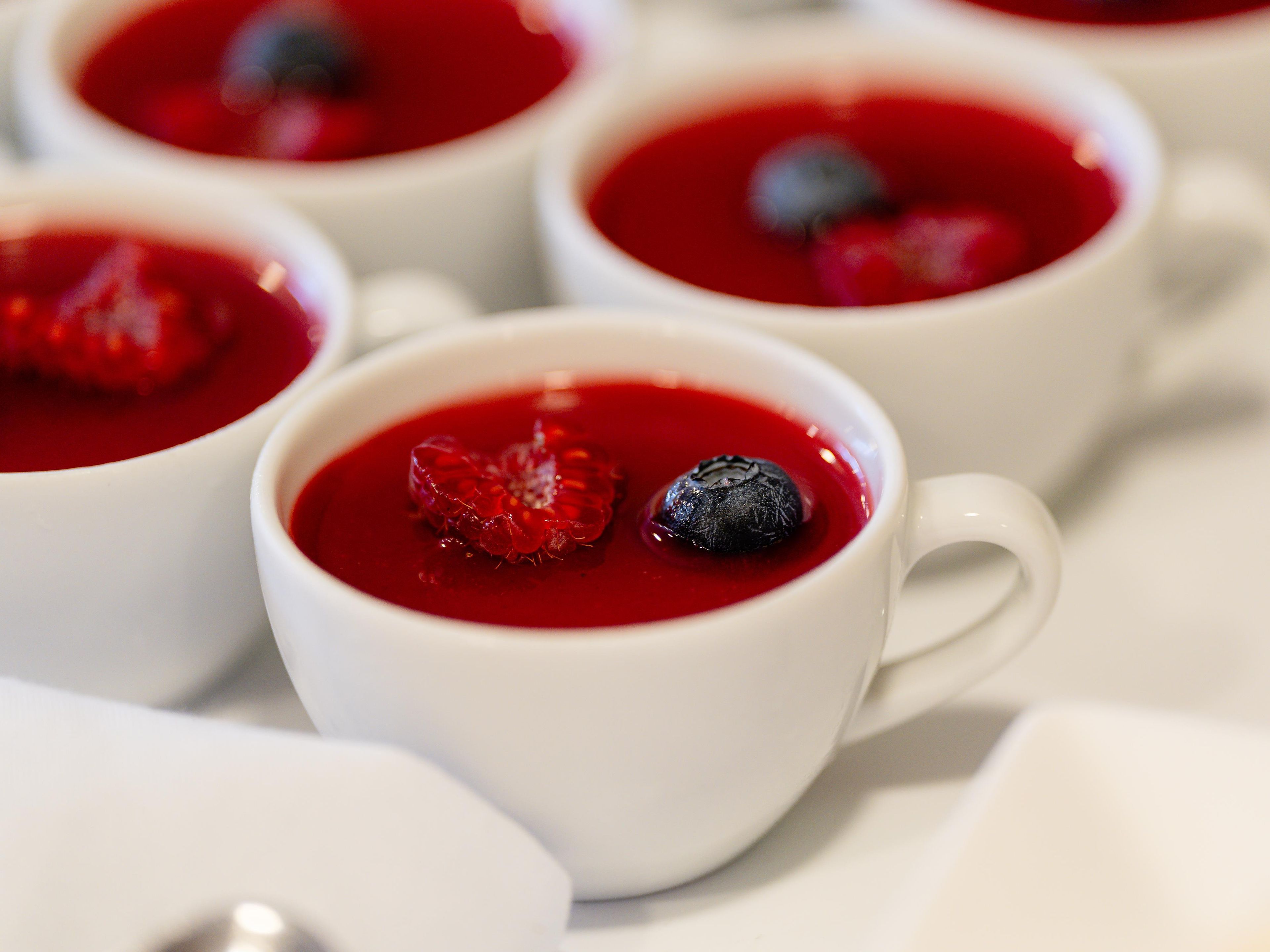 A series of white cups with red contents and berries.