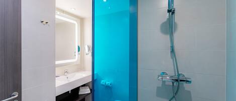 A modern bathroom with a glass partition, a shower, a toilet, and a sink.