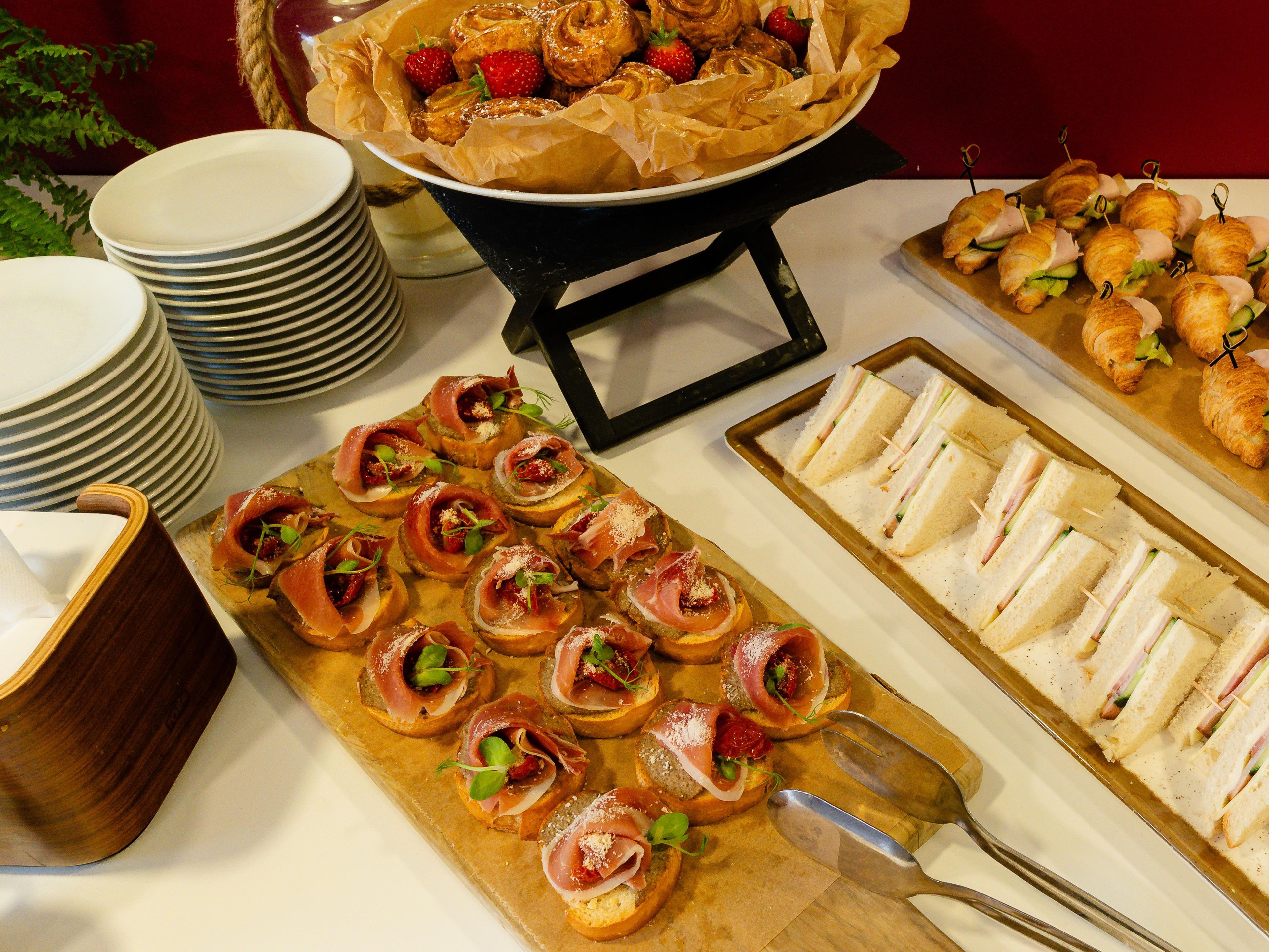 Een buffet met diverse gerechten, waaronder belegde broodjes, croissants en hapjes.