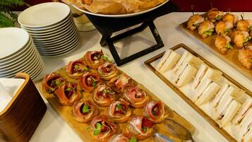 Een buffet met diverse gerechten, waaronder belegde broodjes, croissants en hapjes.