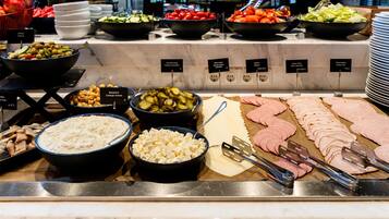 A buffet with various food items including olives, cheese, and sliced meats.
