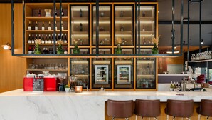 A bar area with a marble countertop, multiple shelves with bottles, and bar stools. - Park Inn by Radisson Riga Valdemara (Riga)
