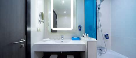 Casa de banho moderna com lavatório branco, espelho iluminado, parede de chuveiro azul e banheira.