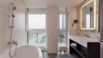 Un baño moderno con bañera, ducha y ventanas amplias con vistas a la ciudad.