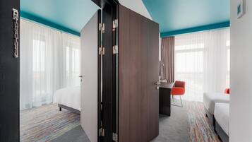 A hotel room with a large wardrobe, a desk, a chair, and a bed.