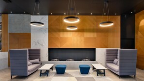 A modern lounge area with a sofa, two blue ottomans, a small table, and a fireplace. - Park Inn by Radisson Riga Valdemara (Riga)
