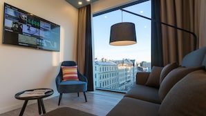 Una sala de estar moderna con un ventanal grande, un sofá, un sillón y una mesita.