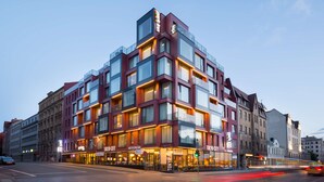 Un hotel moderno con varios pisos, ventanas amplias y una entrada destacada con señalización.