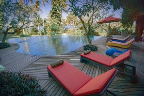 A wooden deck with a pool, lounge chairs, and an umbrella. - Villa Delmara At Balian Beach (Selemadeg)