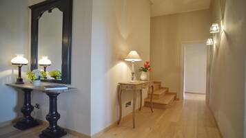 A hallway with a marble table, two lamps, a mirror, and a staircase.