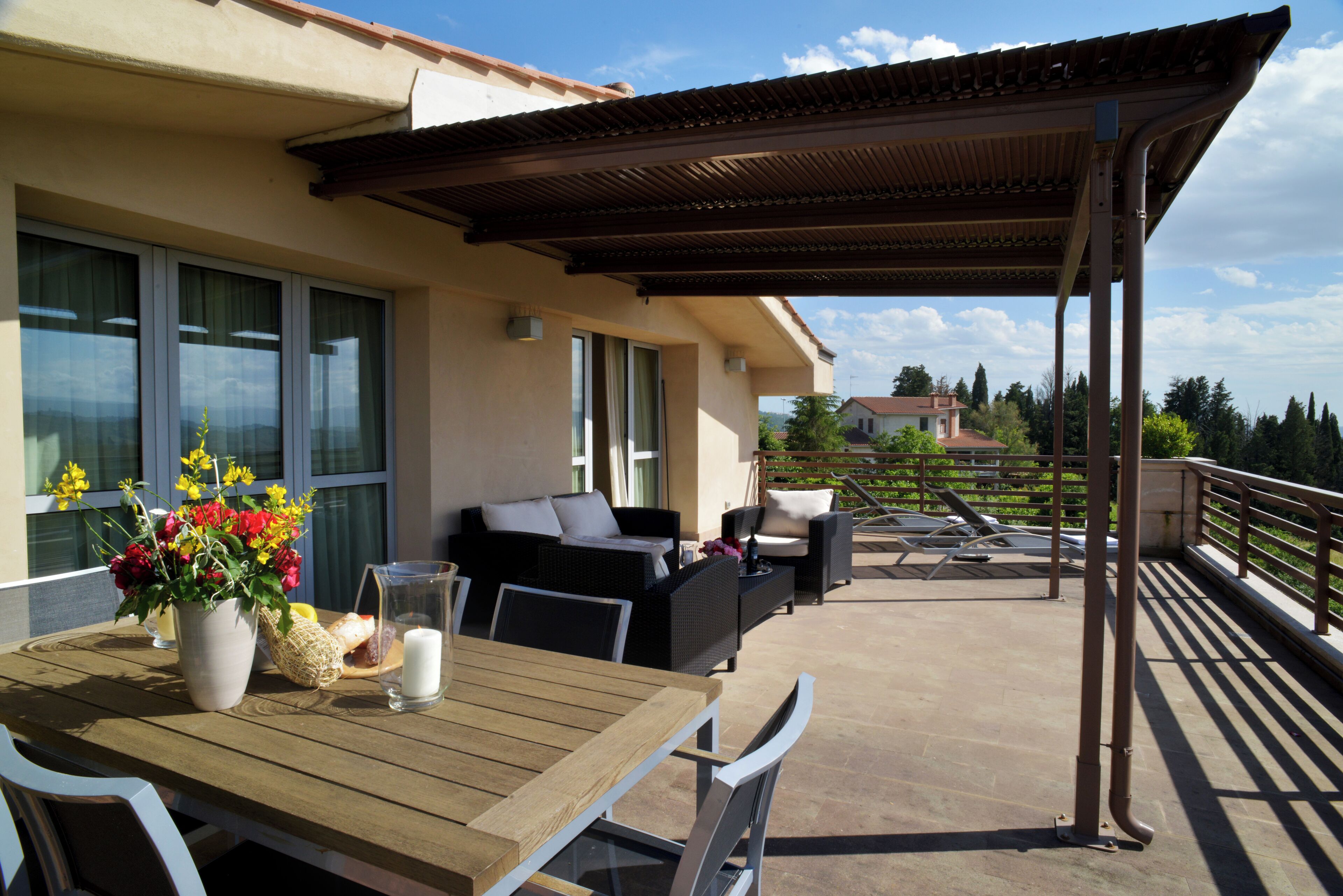 An outdoor patio with a wooden table, wicker furniture, and a pergola.