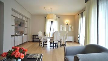 A modern living room with a dining area, a kitchen with cabinets, and a large window with curtains.