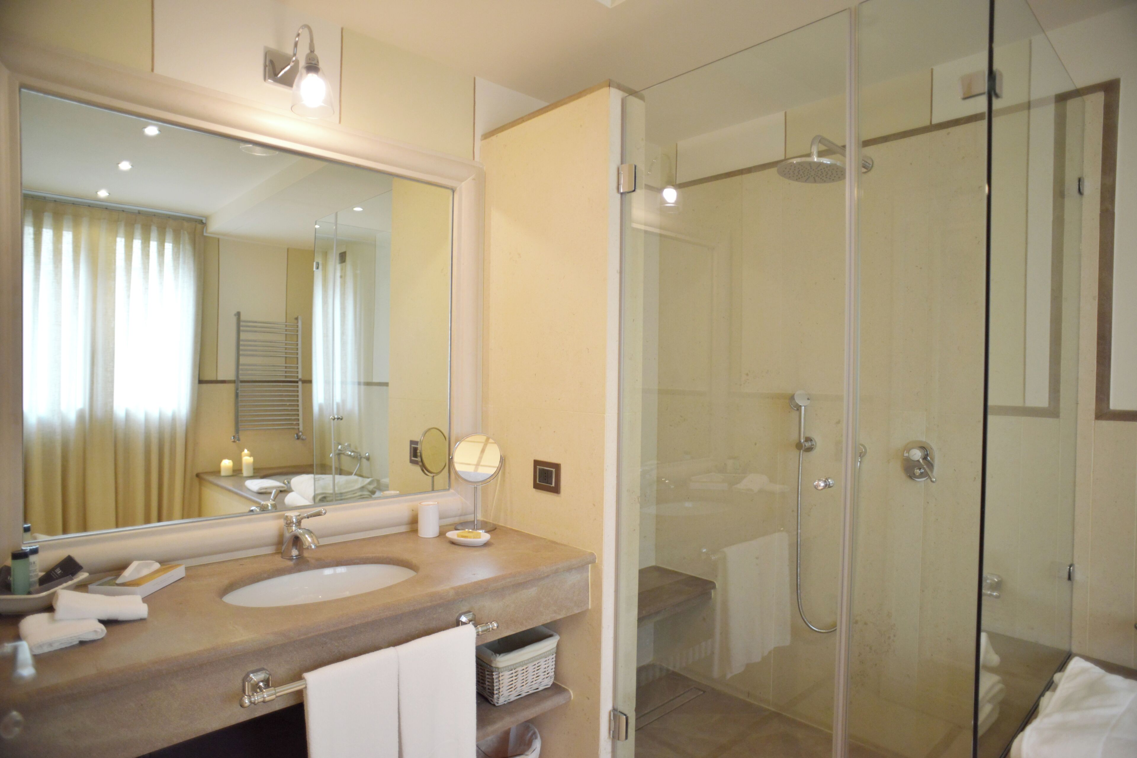 A bathroom with a large mirror, two sinks, a glass shower enclosure, and a towel rack.