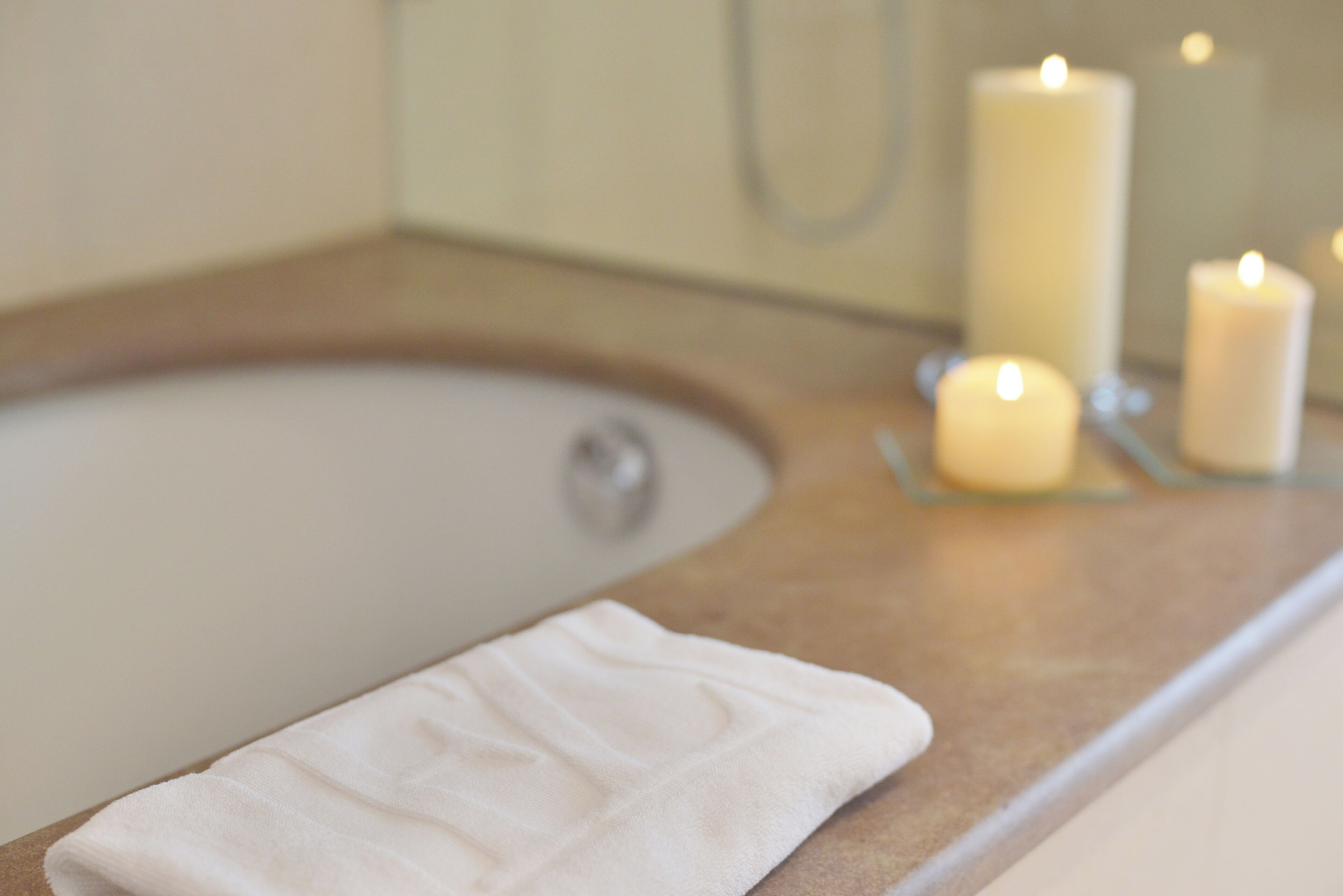 A bathroom with a bathtub, a towel, and candles.