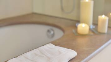 A bathroom with a bathtub, a towel, and candles.