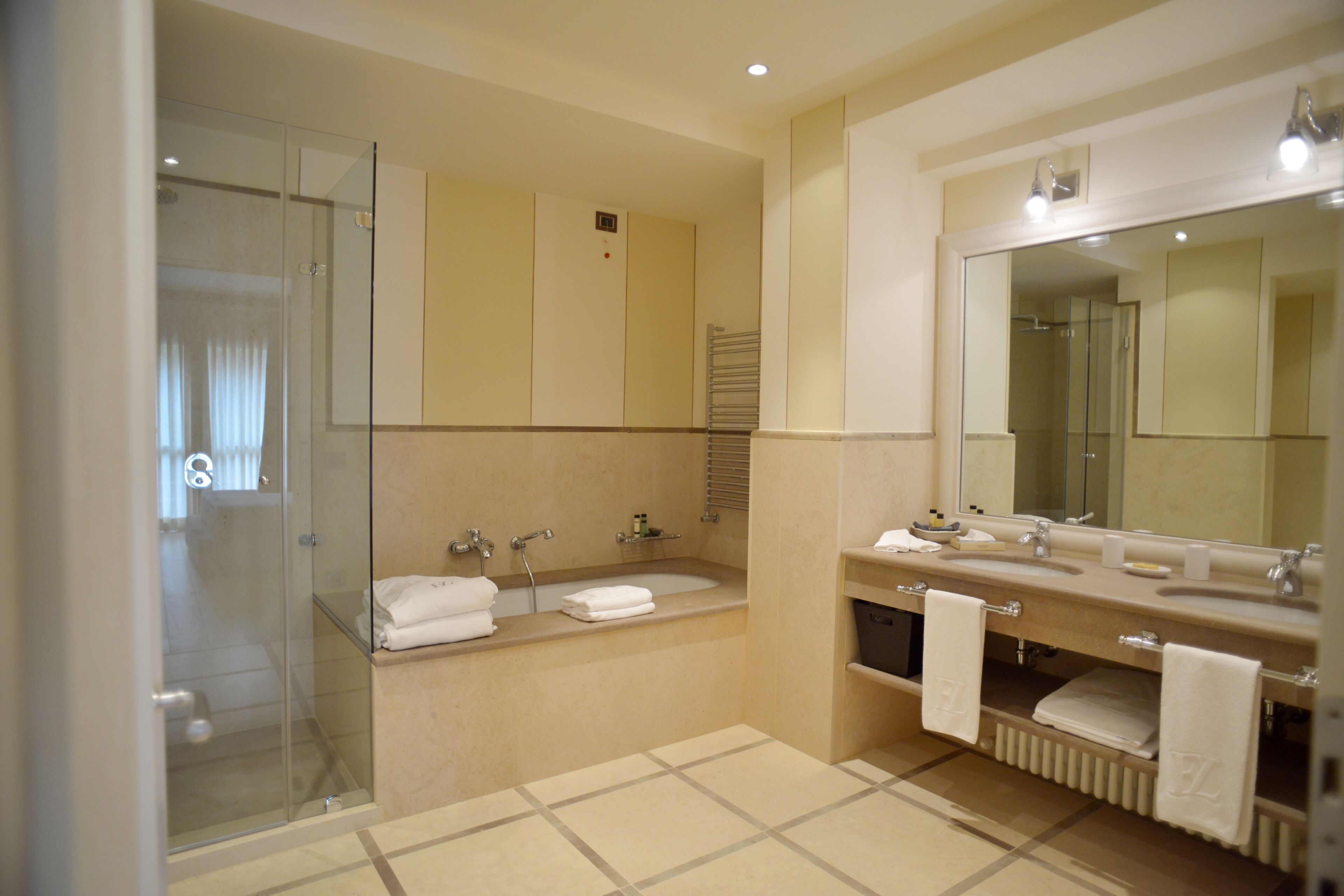 A modern bathroom with a glass shower enclosure, a bathtub, and a vanity with two sinks.