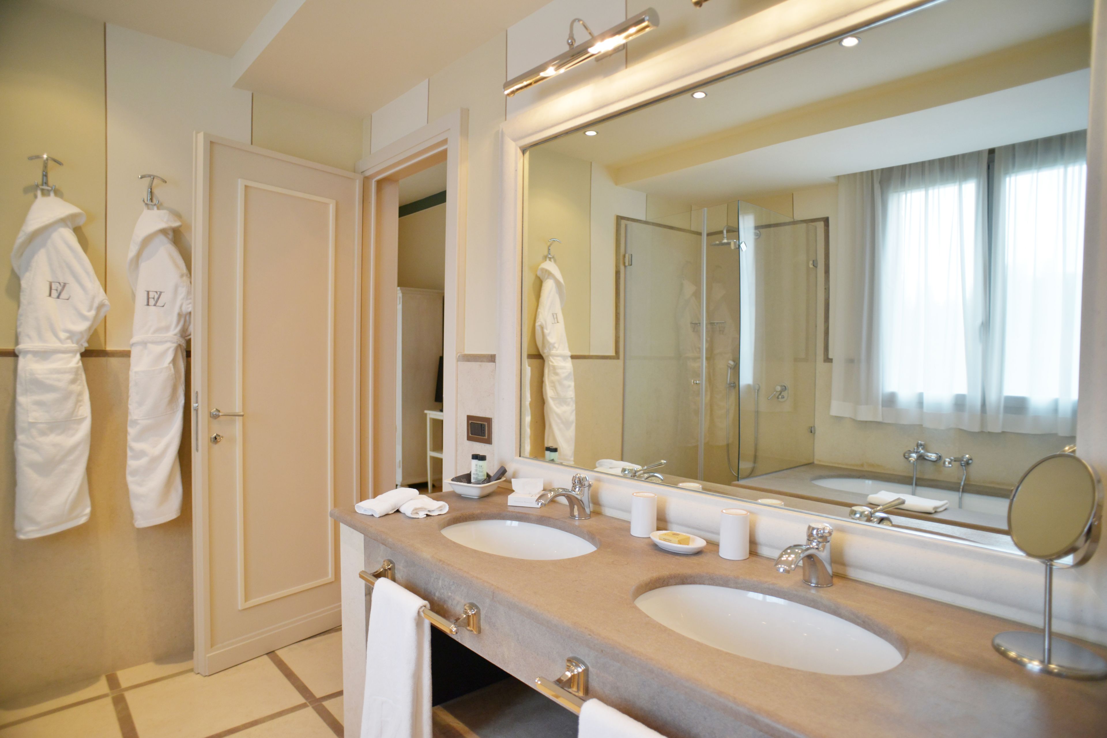 A bathroom with two sinks, a large mirror, and a walk-in shower.