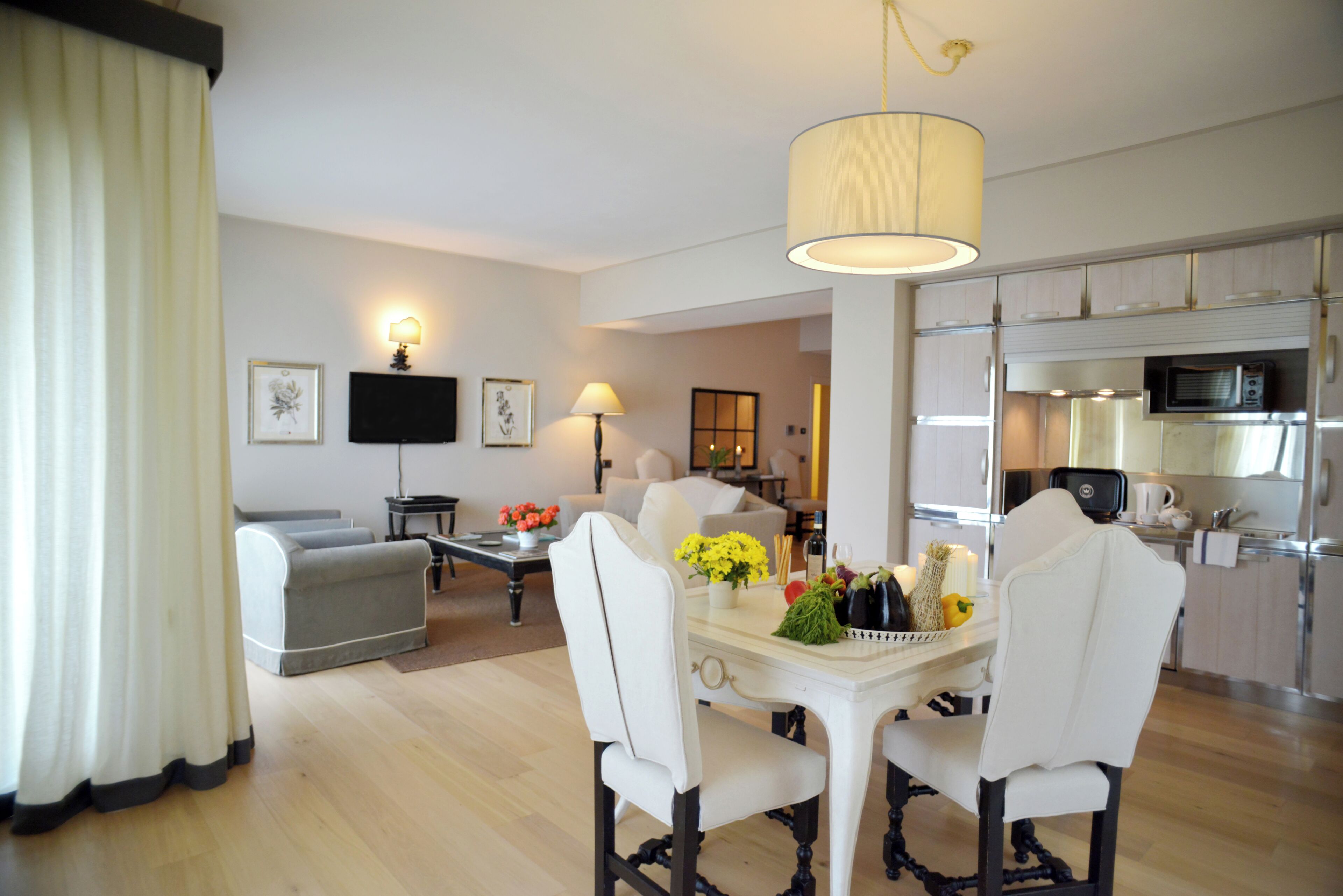Una sala de estar moderna con comedor, cocina y un televisor de pantalla plana en la pared.