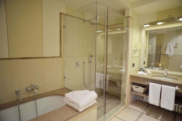 A modern bathroom with a glass-enclosed shower, a bathtub, and a vanity with a mirror and towel rack.