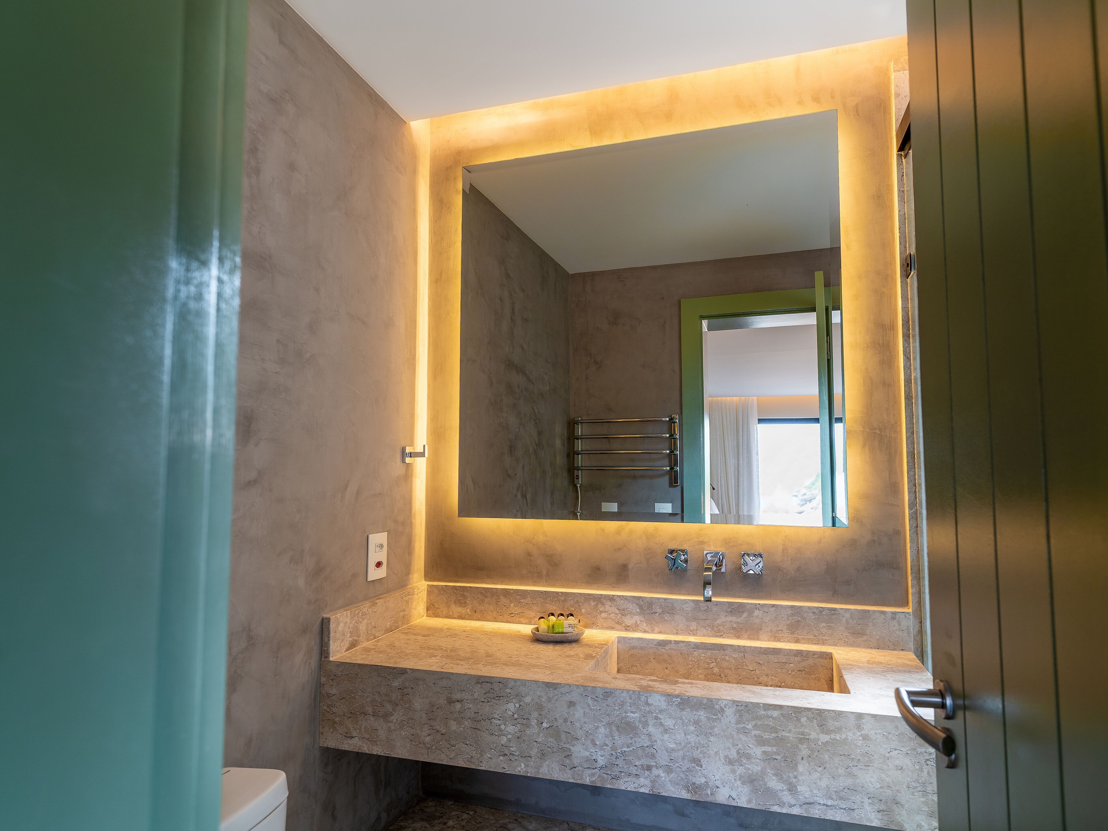 A bathroom with a large mirror, a sink, and a towel rack.