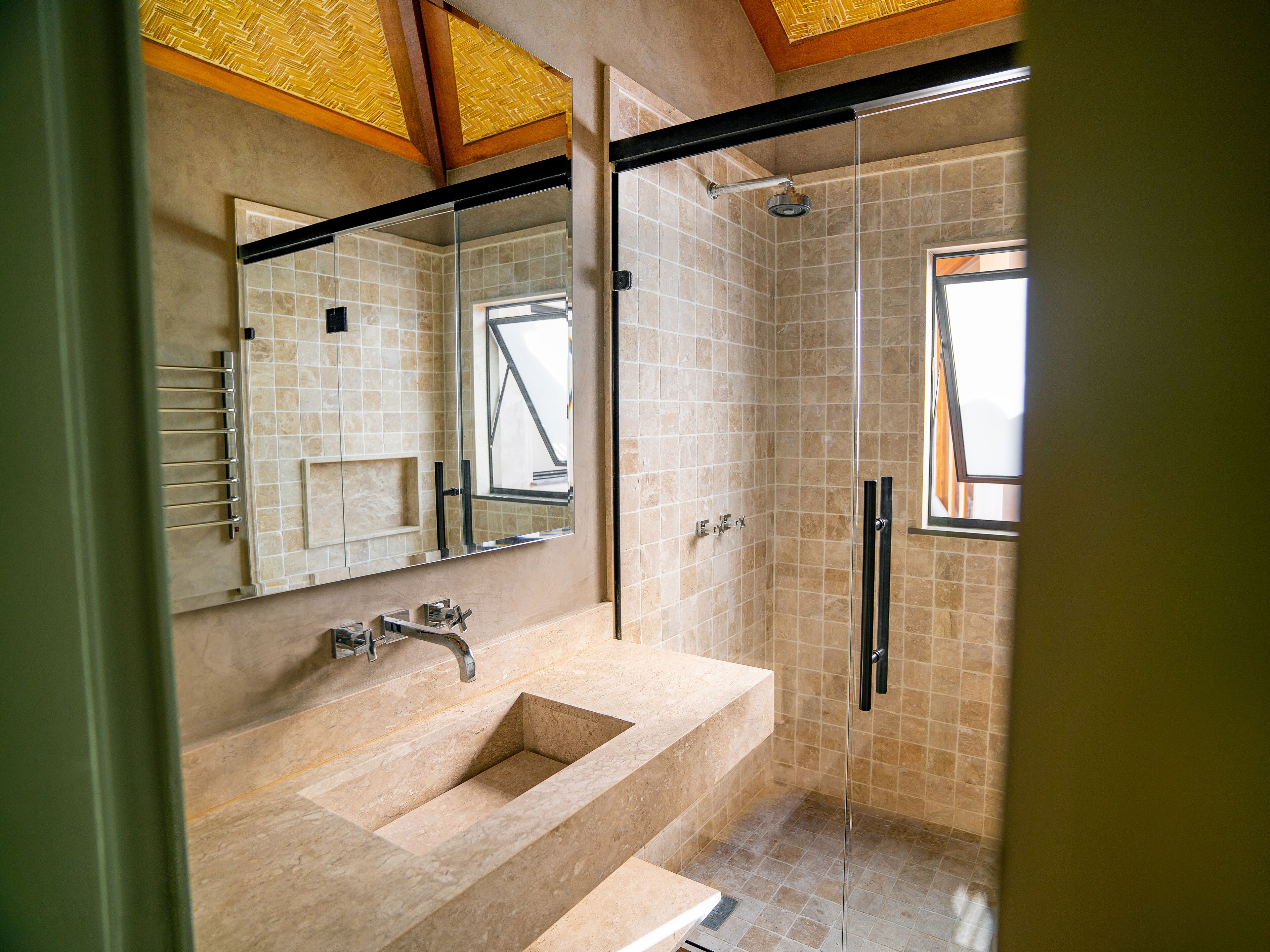 Une salle de bain moderne avec un grand miroir, un lavabo et un espace douche.