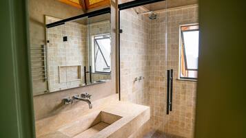 Un baño moderno con un espejo grande, un lavabo y una zona de ducha.