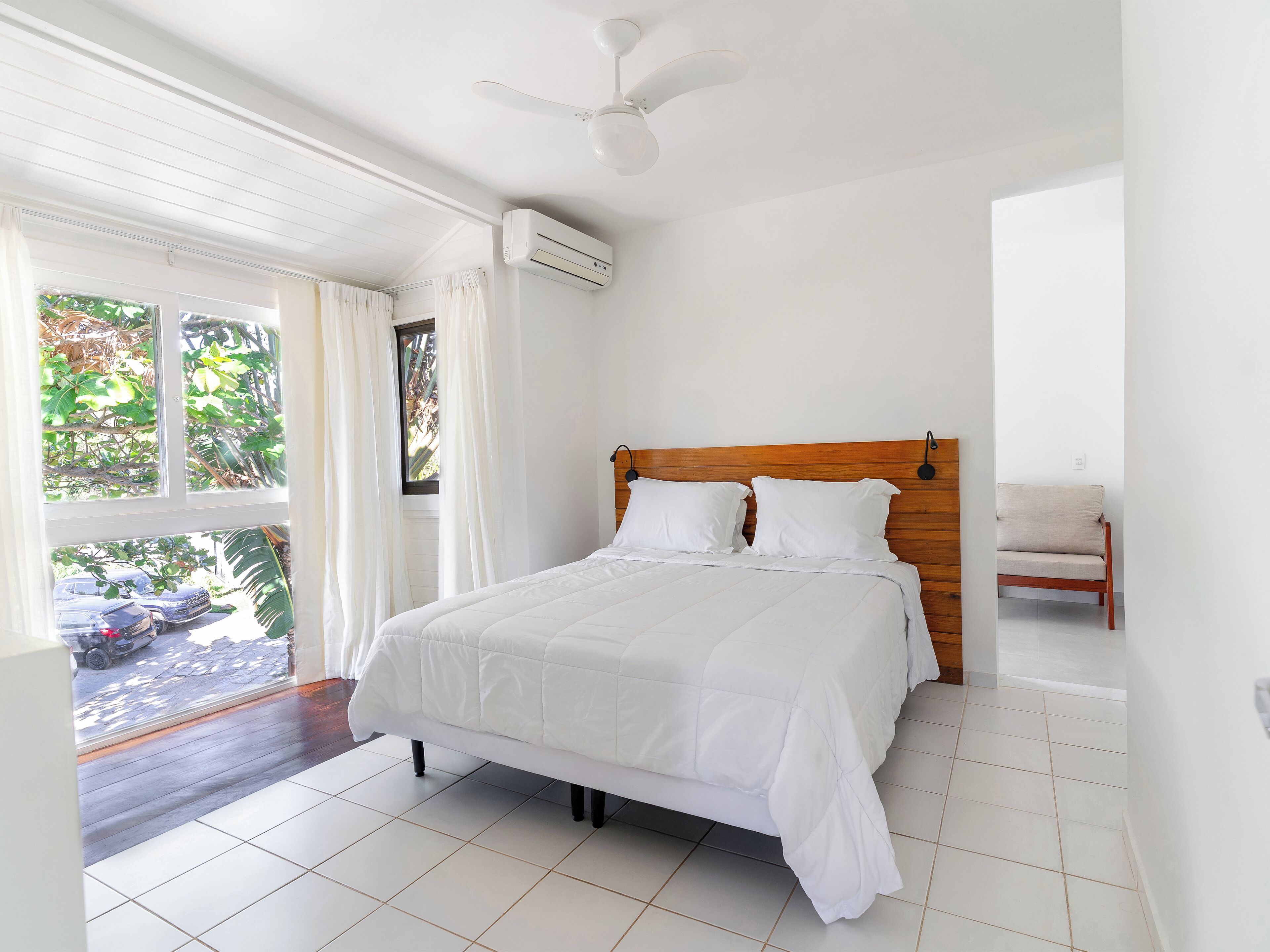 A bedroom with a bed, a ceiling fan, and a window with curtains.
