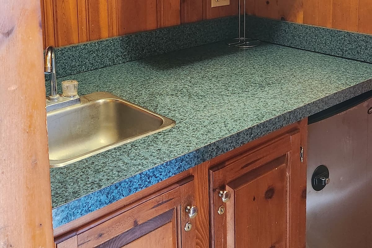 A kitchen with wooden cabinets, a granite countertop, a stainless steel sink, and a microwave.