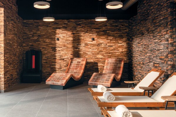 Un cuarto de spa con paredes de madera, tres sillones de masaje y una sauna.