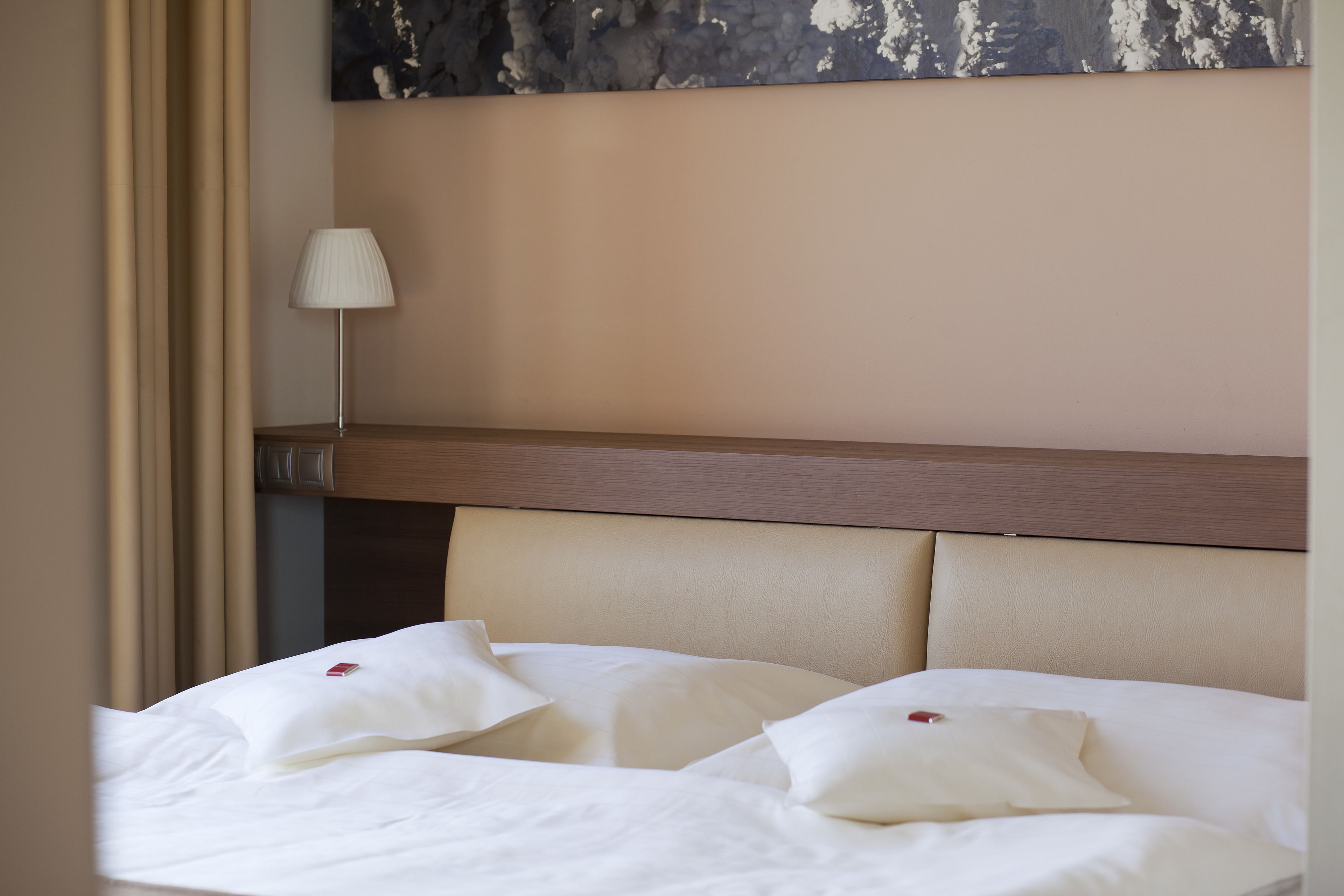 Une chambre d’hôtel avec un lit, une table de chevet, une lampe et un tableau au mur.