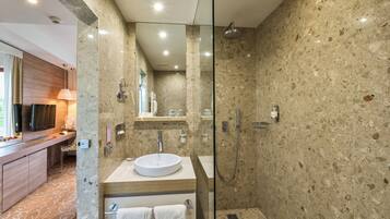 A modern bathroom with a glass-enclosed shower, a sink with a marble countertop, and a wooden vanity.