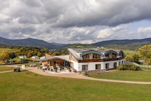 Un edificio moderno con techo curvo, rodeado por un césped cuidado y vistas a montañas distantes.