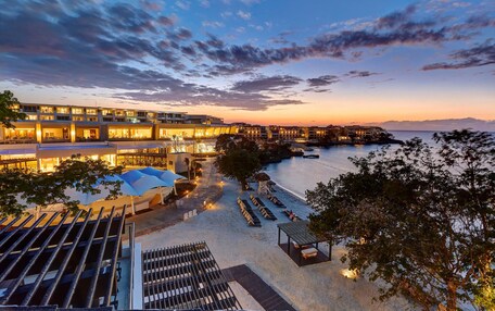 A hotel with a pool area, outdoor seating, and a view of the sea.