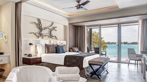 Habitación de hotel moderna con una cama grande, zona de estar, bañera y balcón con vista al mar.