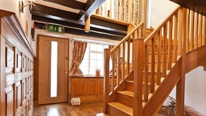 Una escalera de madera que sube a un espacio superior con una ventana y una puerta.