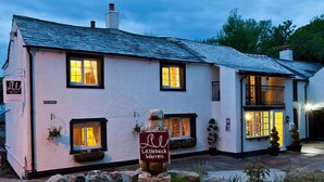 Un edificio blanco con varias ventanas, un letrero que dice "Littlebeck Warren" y una escultura de piedra de un gato.