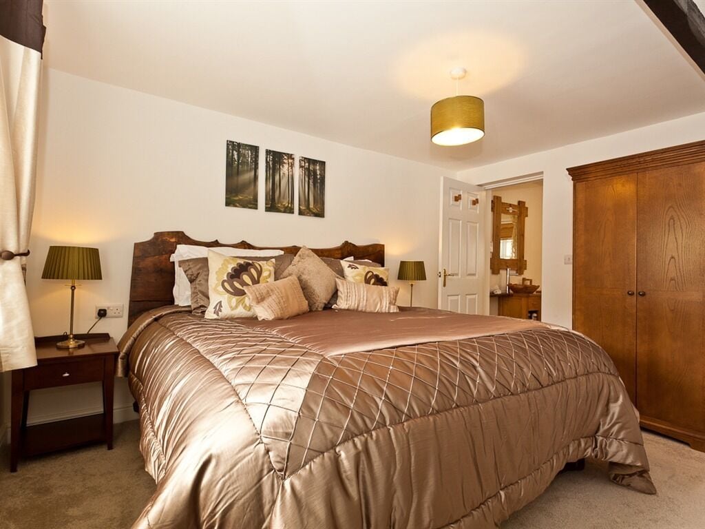 A bedroom with a large bed, a wooden wardrobe, and a door leading to another room.
