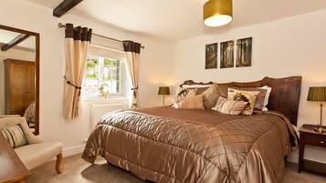 A bedroom with a large bed, a wooden headboard, a nightstand, a lamp, a window with curtains, and a mirror.
