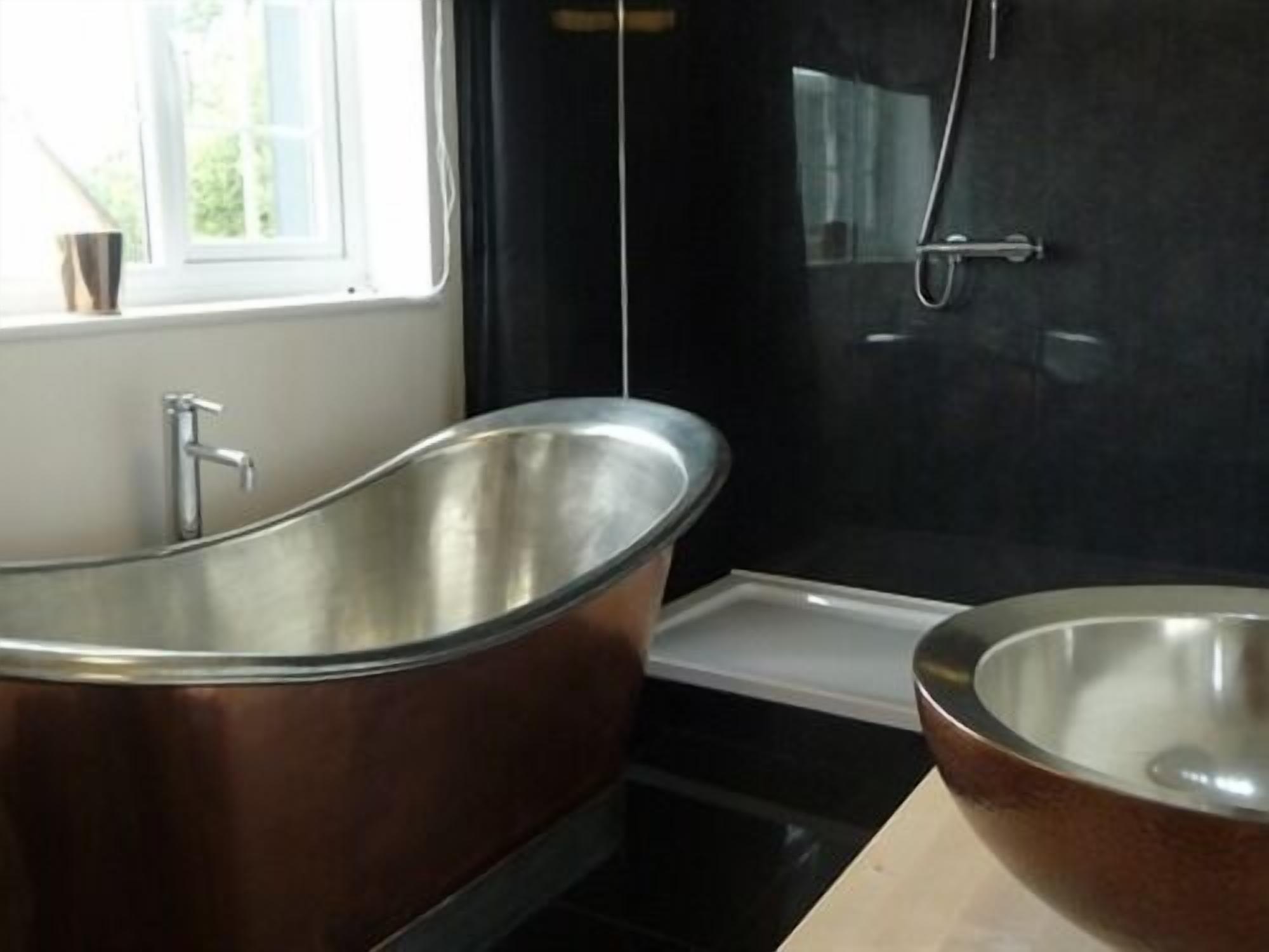A modern bathroom with a freestanding bathtub, a large mirror, and a sink.