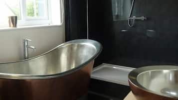 A modern bathroom with a freestanding bathtub, a large mirror, and a sink.
