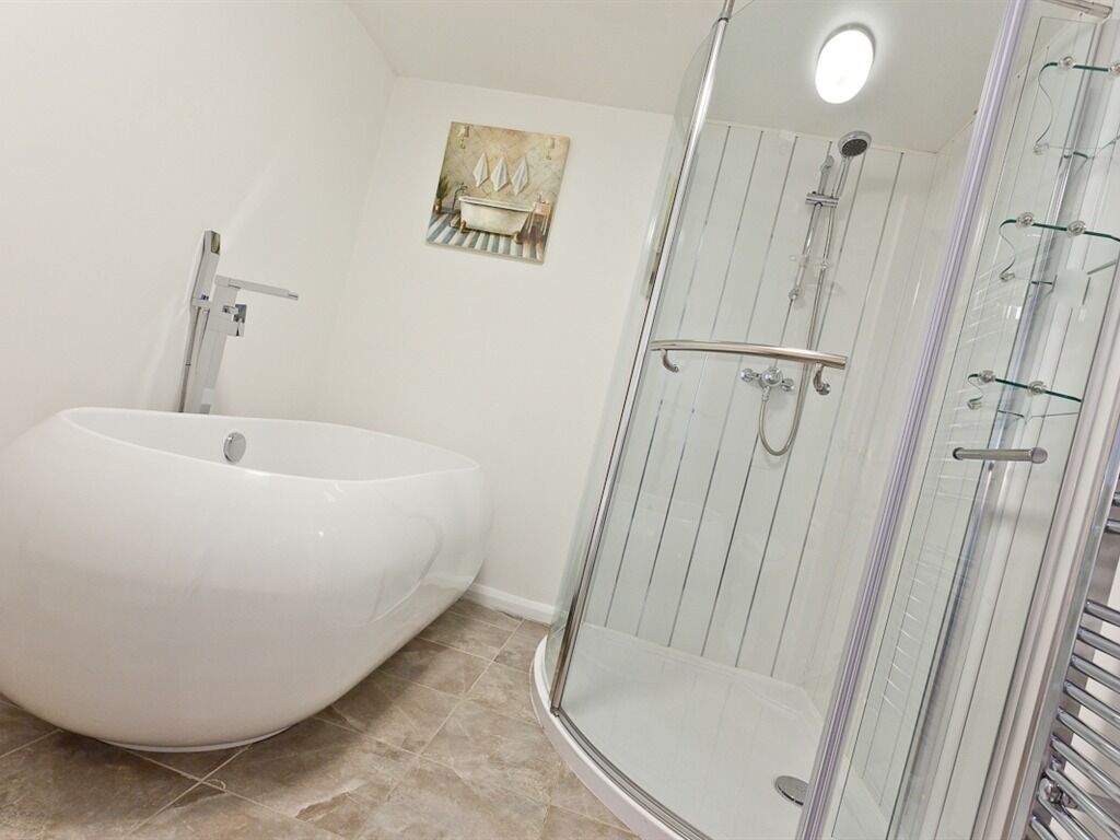 A bathroom with a freestanding bathtub, a glass-enclosed shower, and a wall-mounted sink.